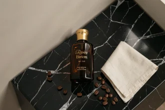 Flacon Armani Code Profumo posé sur marbre noir avec grains de café et pochette lin crème, style flat lay luxe